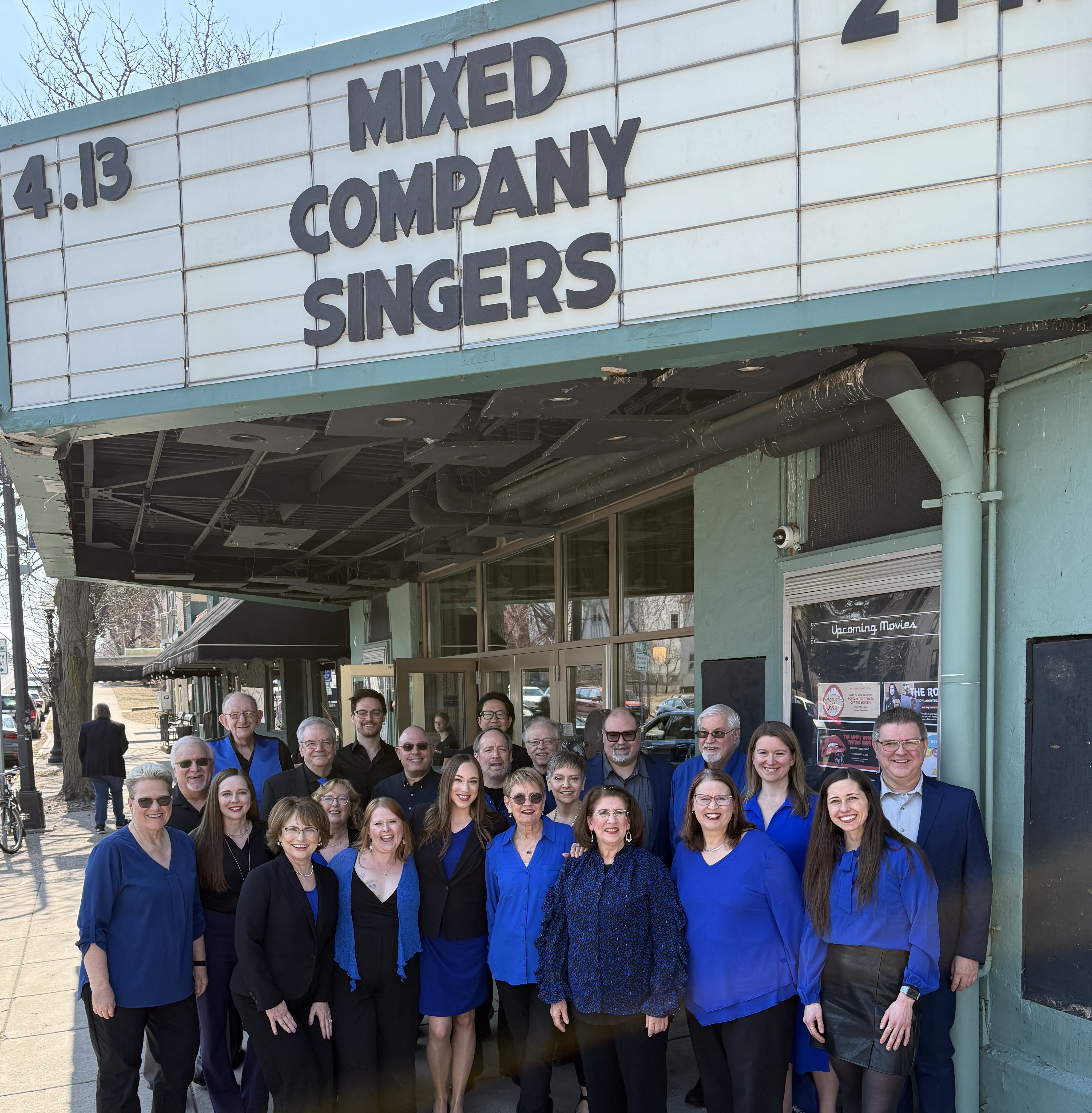 Group picture of singers standing under the Parkway Theater marquee